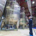 Worker inspecting industrial storage tanks during industrial tank cleaning and maintenance operations