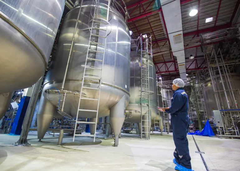 Worker inspecting industrial storage tanks during industrial tank cleaning and maintenance operations
