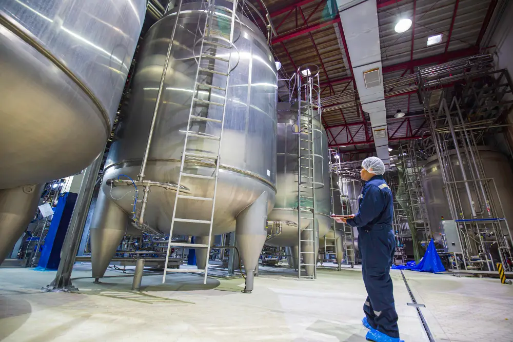 Worker inspecting industrial storage tanks during industrial tank cleaning and maintenance operations